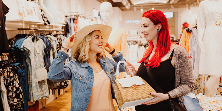 Zwei Frauen probieren voller Freude in einem Geschäft Kleidung an