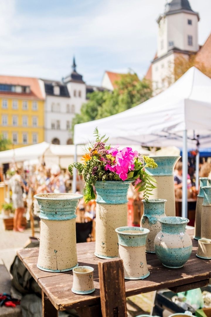 Verschiedene Vasen in grün-beiger Lasur, in einer ein Blumenstrauß auf dem Jenaer Töpfermarkt