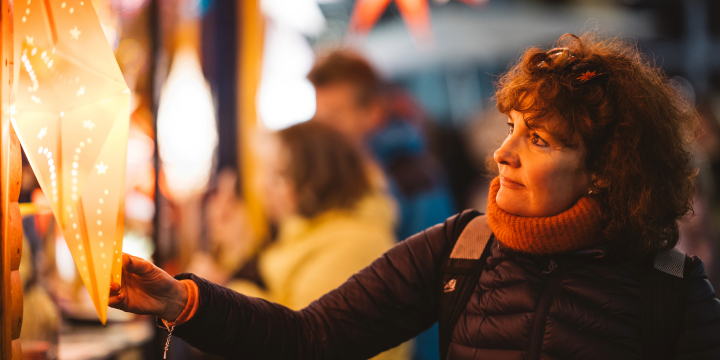 Eine Frau betrachtet einen leuchtenden Stern an einem Stand des Jenaer Weihnachtsmarktes