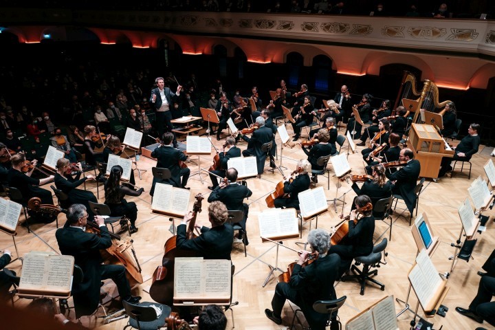 Jenaer Philharmonie im Volkshaus: Bühnensicht auf Musiker:innen mit Notenblättern, Simon Gaudenz dirigiert