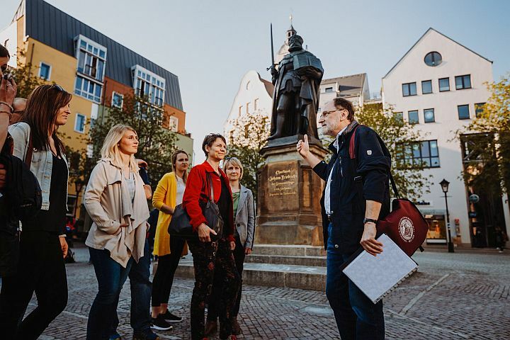 Eine Stadtführung macht Halt am Hanfried-Denkmal auf dem Marktplatz in Jena